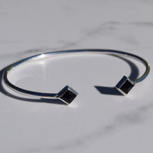 Load image into Gallery viewer, Silver bracelet with black square stones on a marble surface